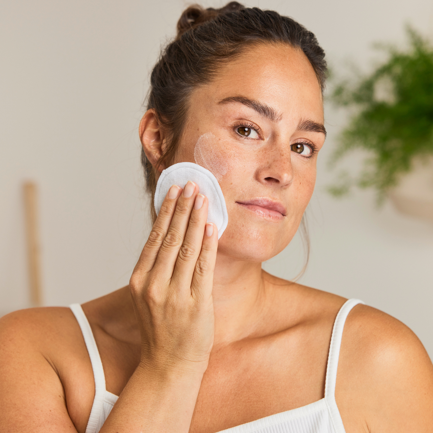 Žena si čistí pleť v koupelně.