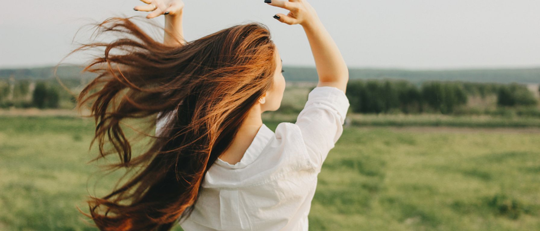 žena s dlouhými vlasy stojící na poli