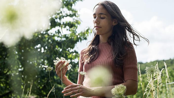 A woman in a green field during a sunny day