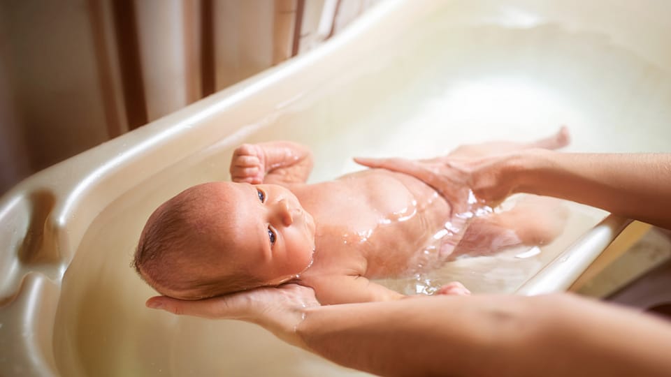 rodič koupe miminko ve vaničce