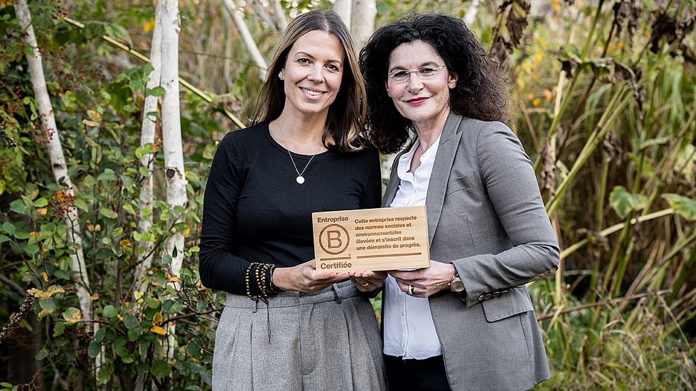 Nadine Santiago and Tina Müller holding the wooden B Corps Logo